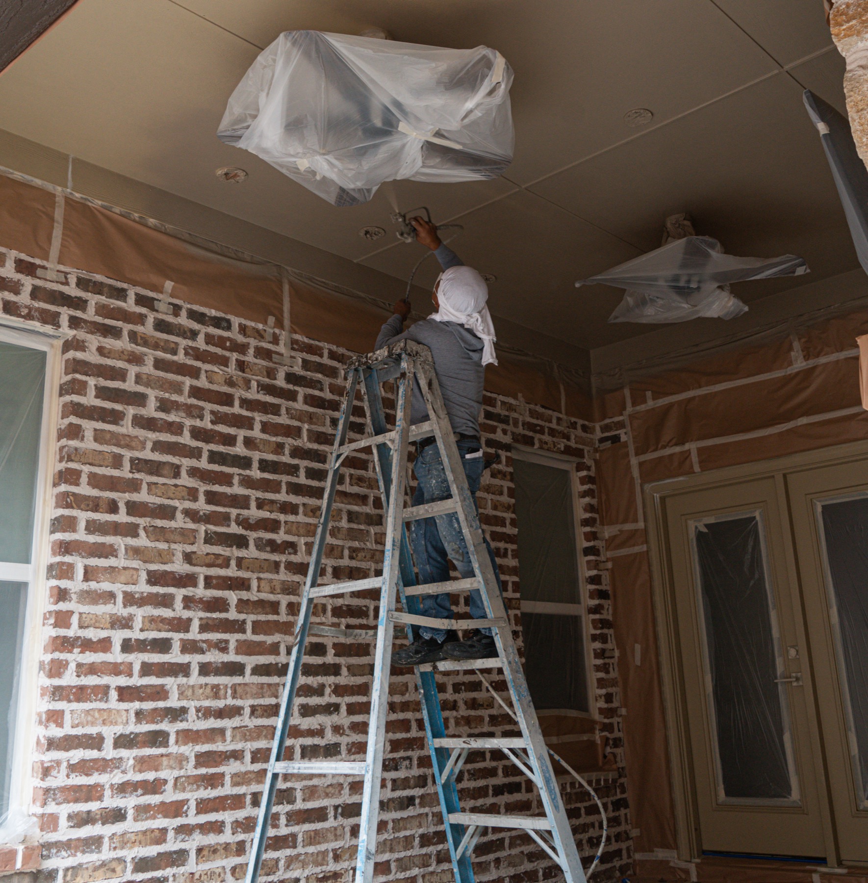 Optimized Painting Co. professional spraying a ceiling with careful masking